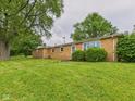 View of a brick home exterior with a well-manicured lawn and lush trees, offering a relaxing outdoor space at 203 Plum E St, Frankton, IN 46044