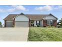 Charming single-story home featuring a manicured lawn, well-kept landscaping, and a two-car garage, perfect for curb appeal at 2308 E Mill Stream Dr, Greenfield, IN 46140