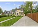 Charming yellow two-story home showcasing a lush lawn and long driveway at 5715 Oak Ave, Indianapolis, IN 46219