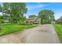Long driveway leading to a beautiful two-story home with mature trees and landscaping, providing a serene setting at 7502 Colony Cir, Indianapolis, IN 46260