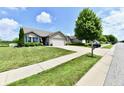 Well-maintained single-story home with an attached garage, manicured lawn, and tree-lined street at 9022 Hosta Way, Camby, IN 46113