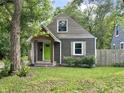 Quaint home with a charming wood porch and vibrant green front door, nestled amongst mature trees at 1601 E 44Th St, Indianapolis, IN 46205