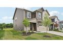 Two-story home with green grass, brown and beige siding, attached two car garage, and covered front porch at 1911 Goodwin Pl, Westfield, IN 46074