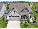 Aerial front view of a charming home featuring a two-car garage, landscaped lawn, and cozy front porch with rocking chairs at 19959 Cowie Ln, Westfield, IN 46074