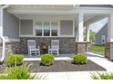 Inviting front porch features white rocking chairs, brick accents, and meticulous landscaping for a cozy curb appeal at 19959 Cowie Ln, Westfield, IN 46074