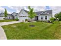 Beautiful home with a green lawn, mature tree, landscaping, and long concrete driveway at 2500 Sand Hollow Dr, Lebanon, IN 46052
