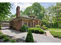 Brick home with a green tile roof, driveway, and well-manicured landscaping at 4455 Broadway St, Indianapolis, IN 46205