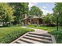 Beautiful brick home with a green roof surrounded by lush greenery and a concrete staircase at 4455 Broadway St, Indianapolis, IN 46205