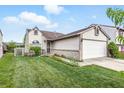 Charming home featuring a manicured lawn, flower beds, and a two-car attached garage at 5305 Traditions Rd, Indianapolis, IN 46235