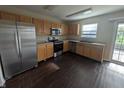 Bright kitchen featuring stainless steel appliances, wood cabinets, and dark floors with access to the patio at 5519 Apple Branch Way, Indianapolis, IN 46237