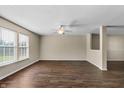 Bright living room featuring dark wood-look floors, a ceiling fan, and windows bringing in natural light at 5519 Apple Branch Way, Indianapolis, IN 46237