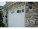Close-up view of the garage door showing the house number, with stone and carriage lights at 7147 Prelude Rd, Brownsburg, IN 46112