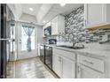 Modern kitchen featuring white cabinets, black appliances, and stylish backsplash at 7468 Countrybrook Dr, Indianapolis, IN 46260