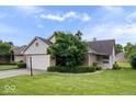 Charming home with a well-maintained lawn, mature tree, and a two-car garage during a bright day at 8213 Thoroughbred Run, Indianapolis, IN 46256