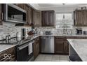 Well-equipped kitchen with stainless steel appliances, mosaic backsplash, sleek countertops, and dark wood cabinetry at 9628 Gull Lake Dr, Indianapolis, IN 46239