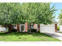 Charming brick home with a two-car garage and mature trees in a well-kept lawn and blue skies overhead at 11820 Stepping Stone Dr, Fishers, IN 46037
