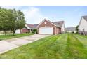 Street view of well-maintained home exteriors with neatly manicured lawns, trees, and concrete driveways leading to garages at 1605 Leisure Way, Greenfield, IN 46140