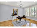 Well-lit office with hardwood floors, a modern desk, plantation shutters, and a contemporary light fixture at 2263 Glebe St, Carmel, IN 46032