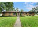 Beautifully landscaped front yard with a brick ranch-style house surrounded by mature trees at 2750 Chamberlin Dr, Indianapolis, IN 46227