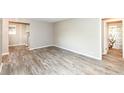Open-concept living room with wood-look flooring, neutral walls, and a view into the kitchen and bathroom at 3938 N Grand Ave, Indianapolis, IN 46226