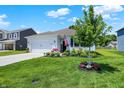 Lovely home with a well-maintained lawn, a young tree, and colorful flower arrangements enhancing its appeal at 5120 Woodhurst Ln, Indianapolis, IN 46239