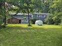 Expansive backyard with well-maintained lawn, lush trees, and a glimpse of the charming home's exterior at 8423 Mud Creek Rd, Indianapolis, IN 46256