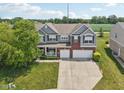 Aerial view of a two-story home with attached garage, surrounded by a green lawn and lush landscaping at 10716 Patoka Rd, Indianapolis, IN 46239