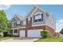 Two-story home with gray siding and brick accents, featuring a two-car garage and landscaped front yard at 10716 Patoka Rd, Indianapolis, IN 46239