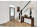 Inviting foyer with hardwood floors, staircase with black railing, stylish table, and artistic decor at 12874 Tradd St, Carmel, IN 46032