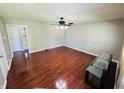 An empty living room featuring hardwood floors, a ceiling fan, and access to other parts of the house at 1345 S Biltmore Ave, Indianapolis, IN 46241