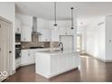 Bright, modern kitchen boasts white cabinetry, stainless steel appliances, a large island, and wood flooring at 19995 Gansett Rd, Westfield, IN 46074