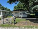Inviting single-story home with a well-kept lawn, fenced yard, and ample shade trees on a sunny day at 2354 Collier St, Indianapolis, IN 46241