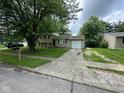 View of home from street, showing tan siding, 1-car garage, and front yard at 2626 Fairhaven Dr, Indianapolis, IN 46229