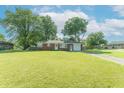 Ranch style house featuring a large yard and a brick facade under a cloudy blue sky at 4625 Beth Ann Dr, Indianapolis, IN 46221