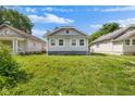 Cozy home with light gray siding, nestled between neighboring houses and lush greenery at 615 Udell St, Indianapolis, IN 46208