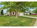 The front yard features lush green grass and mature trees, adding to its curb appeal at 619 Cahill Ln, Indianapolis, IN 46214
