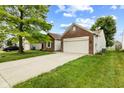 The exterior shows a well-maintained lawn and a two-car garage with ample parking space at 619 Cahill Ln, Indianapolis, IN 46214