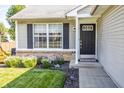 Close-up view of a home's black front door, flanked by a flower garden and a well-maintained lawn at 740 Springmill Dr, Mooresville, IN 46158