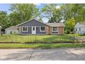 Charming single-story home featuring gray siding, brick accents, and a well-maintained front yard with mature trees at 9319 Rochelle Dr, Indianapolis, IN 46235