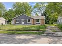 Charming single-story home featuring gray siding, brick accents, and a well-maintained front yard with mature trees at 9319 Rochelle Dr, Indianapolis, IN 46235