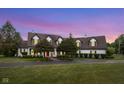 Two-story home featuring a red front door, mature trees, and a pristine lawn at dusk at 10594 Geist Rd, Fishers, IN 46037