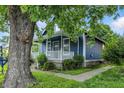Cozy blue home with white trim, featuring a porch and mature trees at 1151 S Randolph St, Indianapolis, IN 46203