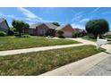 Beautiful brick home featuring a lush green lawn and professional landscaping at 1633 Belfield St, Indianapolis, IN 46217