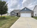Well-maintained single-story home featuring a manicured lawn, two-car garage and vibrant flowerbeds at 1706 Creekwater Pass, Greenfield, IN 46140