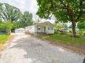 View of single-story home, detached garage, long gravel driveway, and fenced front yard at 2909 S Randolph St, Indianapolis, IN 46203