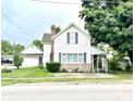 Charming two-story home features a brick chimney, front porch, and lush landscaping, set on a green lawn at 4096 N 200 W, Greenfield, IN 46140