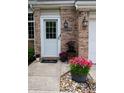 Inviting front door with brick surround, decorative plants, and a welcoming 'hello' mat at 5704 Carrousel Dr, Indianapolis, IN 46254