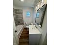 Modern bathroom with wood-look floors, updated fixtures, tub with tile surround, and bright lighting at 7301 E Wiser Ave, Camby, IN 46113