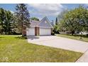 Wide shot of home's brick exterior with three car garage, and long driveway at 8909 Carnation Dr, Noblesville, IN 46060