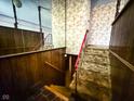 Hallway with a carpeted staircase, wood paneling and eye catching floral wallpaper and mirrored wall at 906 Hemlock St, Shelbyville, IN 46176